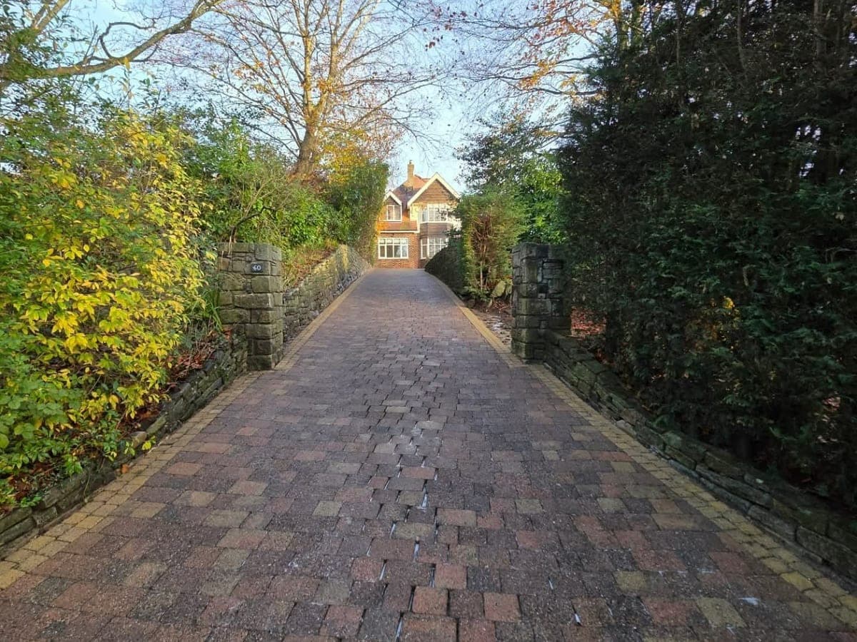 Long block paved driveway darkened with moss, and the same driveway cleaned